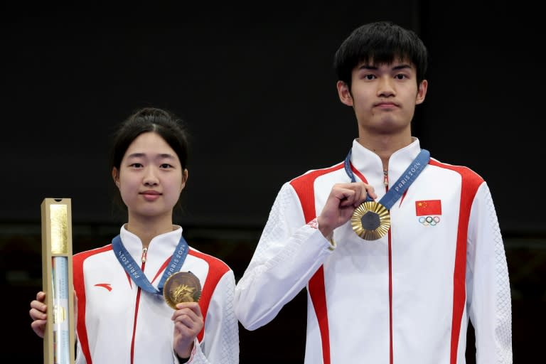 Los chinos Huang Yuting (izquierda) y Sheng Lihao (derecha) posan con el primer oro concedido en los Juegos Olímpicos de París-2024, en la prueba de tira con carabina desde 10 metros en categoría mixta. En Chateauroux (Francia), el 27 de julio de 2024 (ALAIN JOCARD)