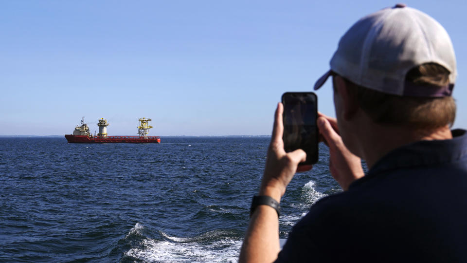 Aaron Smith, President and CEO of the Offshore Marine Service Association, photographs ships installing portions of a wind farm, Tuesday, July 11, 2023, off the coast of Rhode Island. The trade association that represents the offshore service industry is going to great lengths to make sure that jobs go to Americans as the U.S. offshore wind industry ramps up. (AP Photo/Charles Krupa)