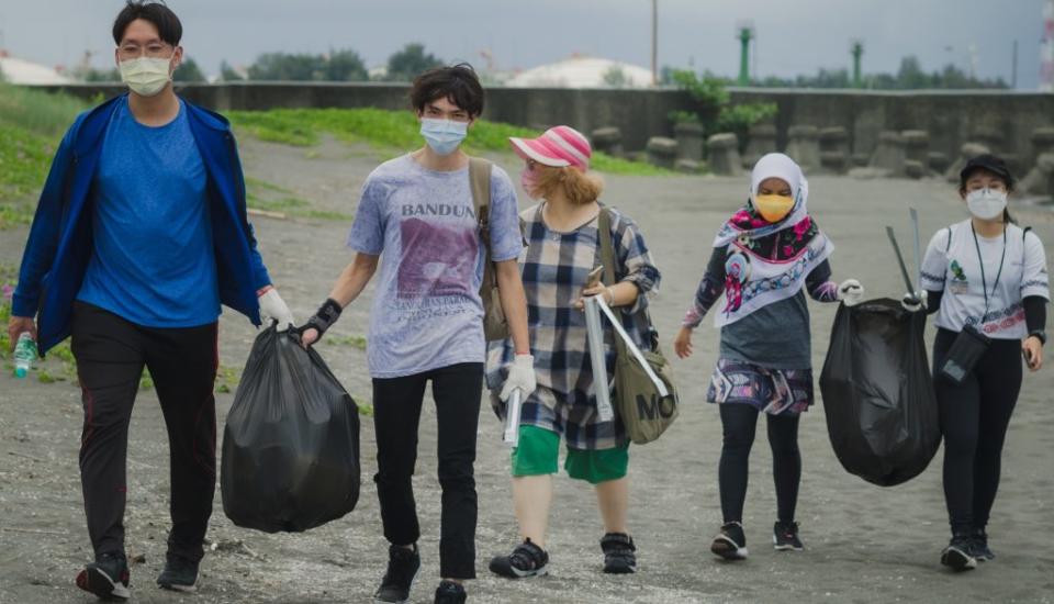 高雄市青年局利用假日帶領國內外青年志工淨灘。（記者許正雄翻攝）