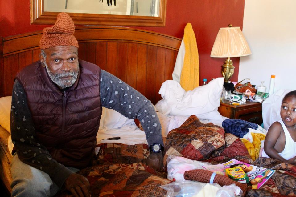 A man living at the Best Night Inn near New Castle on Thursday, Nov. 2 wears a hat provided to him during an outreach event as his grandson looks on.