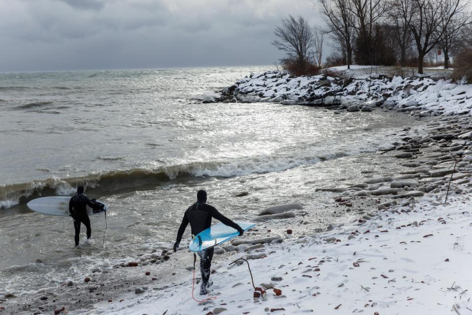 Surfers make their way out to Lake Ontario to surf the waves created by a major winter storm, in Toronto, Saturday, Dec. 24, 2022 (AP)
