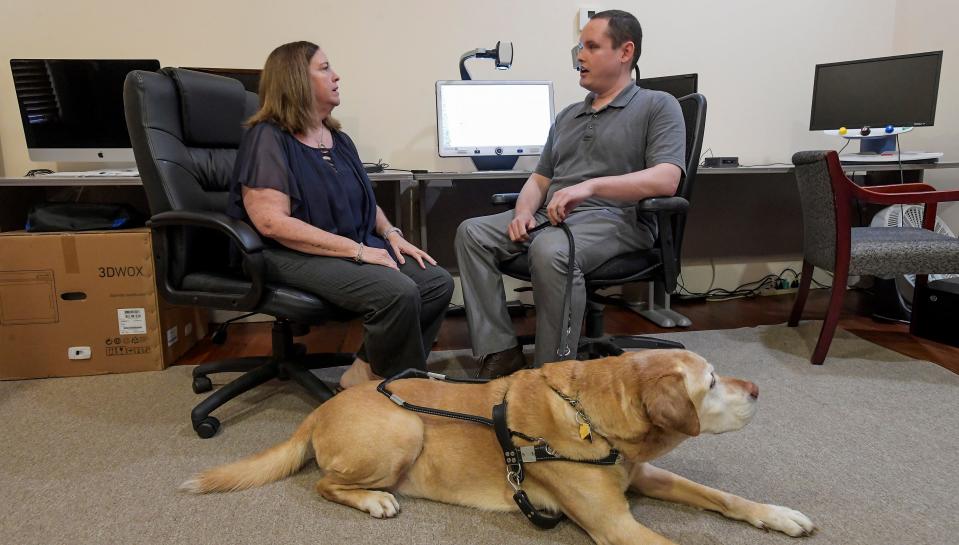 Jenny Savage talks with Collin Frase and his guide dog Archie at the AIDB offices in Montgomery.