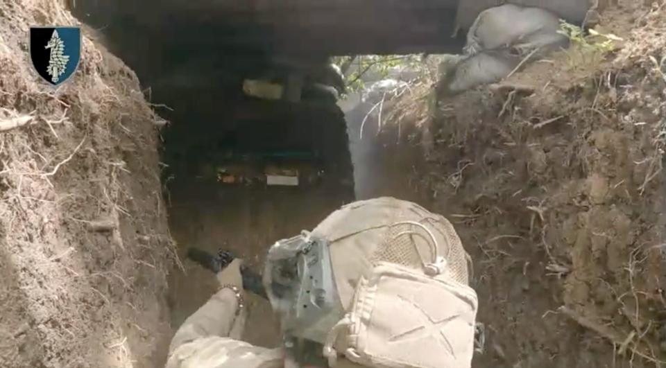 A Ukrainian soldier breaches a Russian trench.