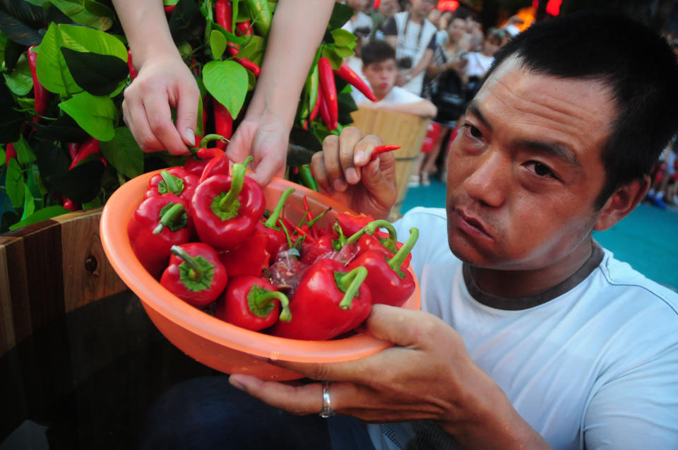 A man sitting in an ice bucket eats peppers during a competition at Song Dynasty Town on July 20, 2016 in Hangzhou, Zhejiang Province of China.&nbsp;