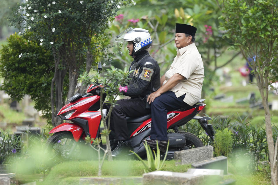 Indonesian Defense Minister and presidential frontrunner Prabowo Subianto rides on the back of a motorbike driven by a police officer during a visit to his father's grave in Jakarta, Indonesia Thursday, Feb. 15, 2024. The wealthy ex-general looks set to be the country's next president after unofficial tallies showed him taking a clear majority in the first round of voting. (AP Photo/Tatan Syuflana)