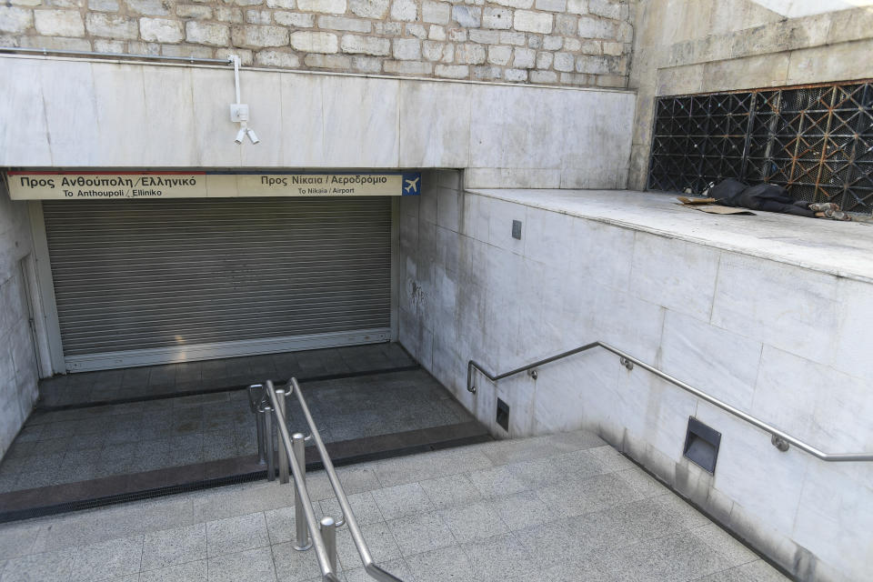 A homeless man sleeps outside a closed entrance of Syntagma metro station during a 24-hour labour strike in Athens, Thursday, June 10, 2021. Greece's biggest labor unions stage a 24-hour strike to protest a draft labor bill being debated in parliament, which workers say will erode their rights. (AP Photo/Michael Varaklas)