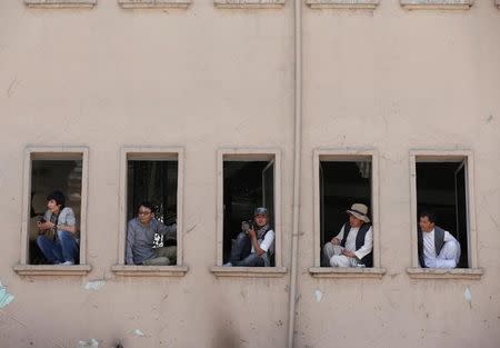 Men watch demonstrators from Afghanistan's Hazara minority during a protest in Kabul, Afghanistan July 23, 2016. REUTERS/Omar Sobhani