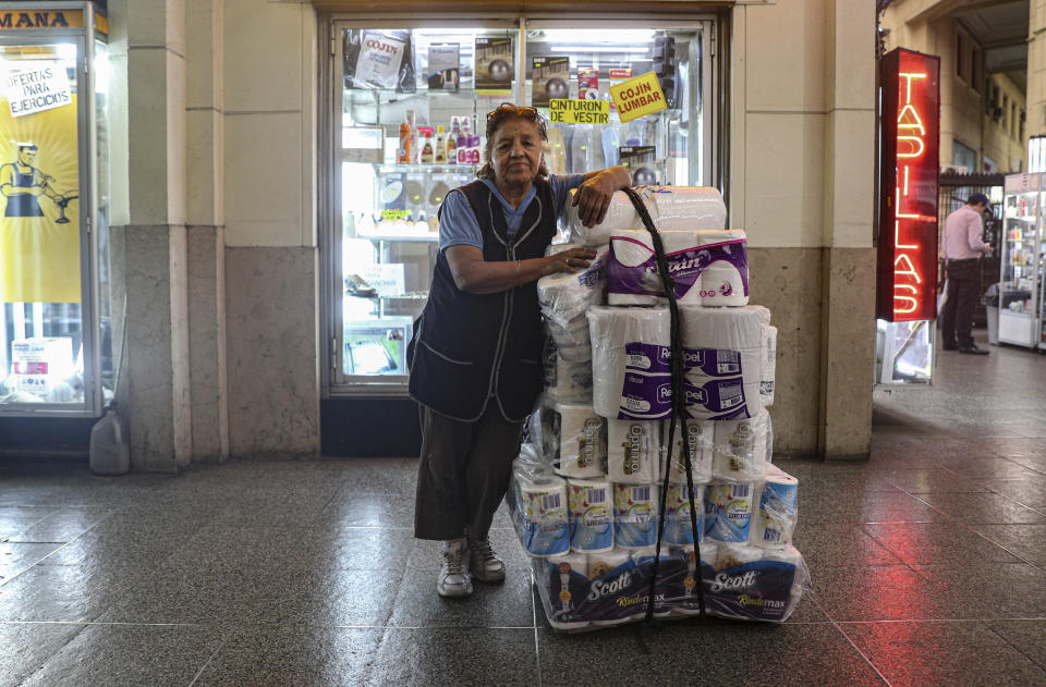 In this Nov. 5, 2019 photo, retired Maria Gonzalez, 77, poses for a photo as she takes a break from selling tissue and toilet paper in downtown Santiago, Chile. Gonzalez says she is tired of waking up, Monday to Friday, to sell toilet paper in the Chilean capital. Her meager $146 monthly pension puts her below the poverty line, which in Chile is around $222 a month. (AP Photo/Esteban Felix)