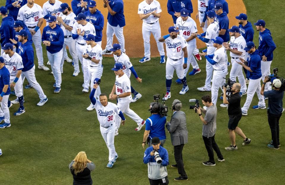 Dodgers manager Dave Roberts tips his cap in appreciation to Dodgers announcer Vin Scully.