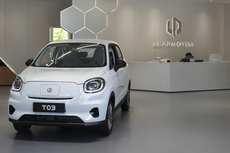 A receptionist sits near the Leapmotor T03 model displayed at a showroom in Hangzhou in eastern China's Zhejiang province on Tuesday, May 14, 2024. European carmaker Stellantis on Tuesday said it had formed a joint venture with the Chinese electric vehicle startup Leapmotor that will begin selling EVs in nine European countries later this year. (AP Photo/Caroline Chen)