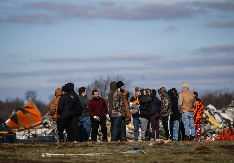 Family and loved ones gather outside the remains of a candle factory destroyed when a deadly tornado ripped through Mayfield, Ky.