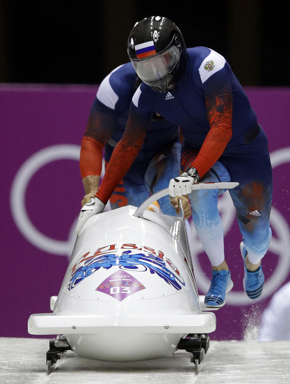 CORRECTS IDS TO ALEXANDER ZUBKOV AND BRAKEMAN ALEXEY VOEVODA - The team from Russia RUS-1, piloted by Alexander Zubkov and brakeman Alexey Voevoda, start their first run during the men's two-man bobsled competition at the 2014 Winter Olympics, Sunday, Feb. 16, 2014, in Krasnaya Polyana, Russia. (AP Photo/Dita Alangkara)