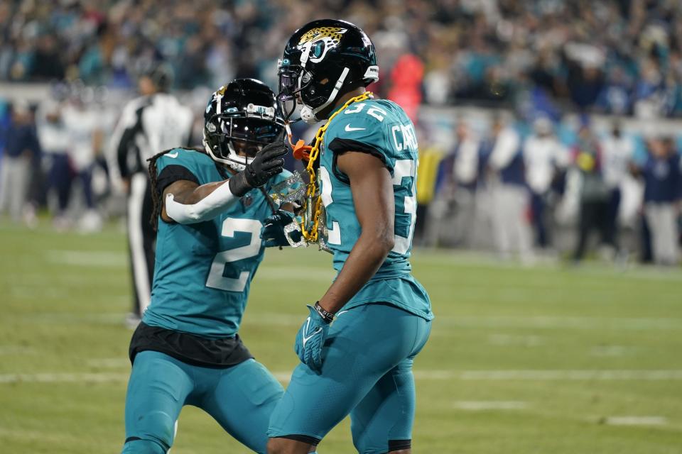 Jacksonville Jaguars cornerback Tyson Campbell (32) celebrates his interception with safety Rayshawn Jenkins (2) with a chain thrown onto the field by a fan in the second half of an NFL football game against the Tennessee Titans, Saturday, Jan. 7, 2023, in Jacksonville, Fla. (AP Photo/John Raoux)