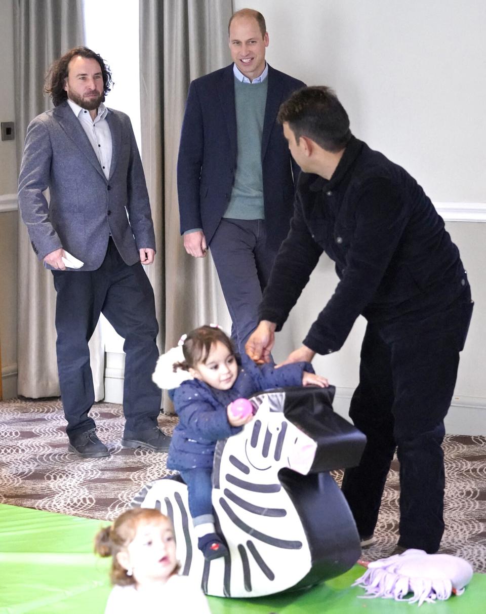 Britain's Prince William, Duke of Cambridge (C) talks with refugees evacuated from Afghanistan in a playroom during a visit to a hotel in Leeds