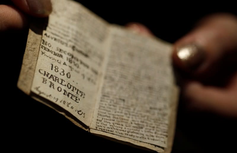 An employee displays the second issue of Young Men's Magazine, a miniature manuscript dated 1830, written by Charlotte Bronte when she was 14 years old, before being put on auction at Drouot auction house in Paris