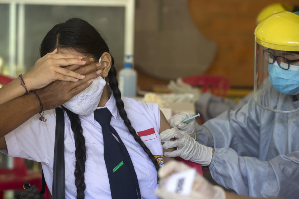 A teenager reacts as she receives a shot of the Sinovac vaccine for COVID-19 during a vaccination campaign at a school in Denpasar, Bali, Indonesia on Monday, July 5, 2021. (AP Photo/Firdia Lisnawati)