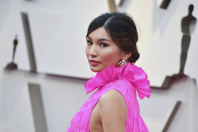 Gemma Chan posing in a ruffled pink dress