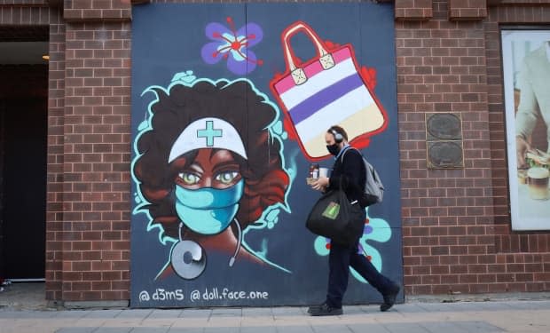 A pedestrian walks past a Rideau Street mural honouring health-care workers on Sept. 16, 2021, during the fourth wave of the COVID-19 pandemic. (Trevor Pritchard/CBC - image credit)