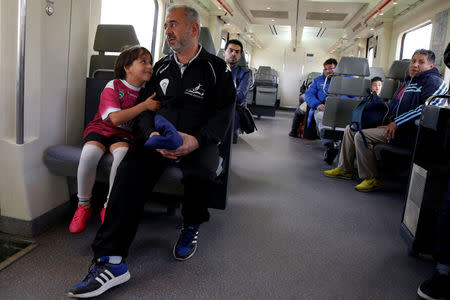 Osama Abdul Mohsen (R), a Syrian refugee, and his young son Zaid sit on a train on their way to a soccer training session in Villaverde, a neighbourhood in Madrid, Spain, April 14, 2016. REUTERS/Sergio Perez