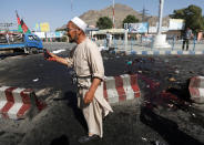 <p>An Afghan man picks up a phone belonging to a victim after a suicide attack in Kabul, Afghanistan, July 23, 2016. (Photo: Omar Sobhani/REUTERS)</p>