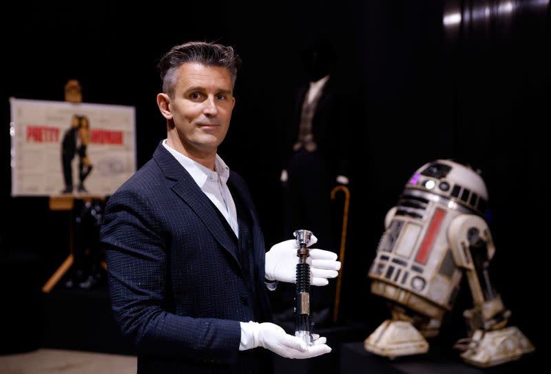 Stephen Lane, CEO of Prop Store, poses for a photograph with Obi-Wan Kenobi's Hero Lightsaber from Star Wars: Revenge of the Sith, at a preview of a movie and TV memorabilia auction in Rickmansworth