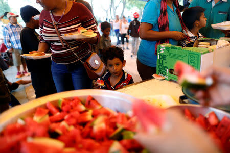 A boy, part of a group of Central American migrants moving in a caravan through Mexico toward the U.S. border, eats watermelon at a shelter set up for the migrants by the Catholic church, in Puebla, Mexico April 6, 2018. REUTERS/Edgard Garrido