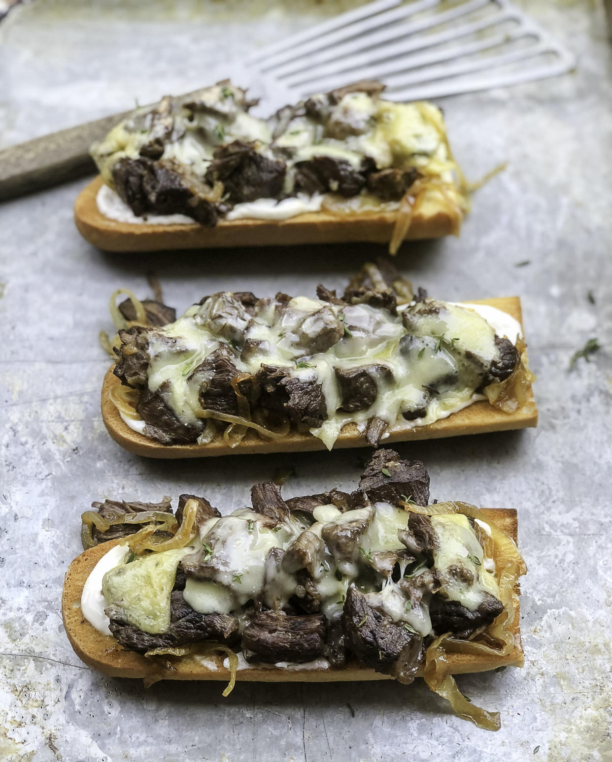 Toasted baguettes slathered in horseradish mayo, topped with roast beef, caramelized onions and cheese (in this case, raclette). (Photo: Kelly Paige)