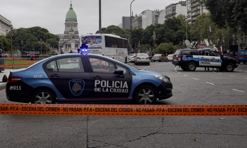 CORRECTS TO CHANGE FROM MOVING VEHICLE TO PARKED CAR - Police cars are parked at the crime scene where Argentine lawmaker Hector Olivares was seriously injured and another man was killed after they were shot at from a parked car near the Congress building, green dome building pictured in background, in Buenos Aires, Argentina, Thursday, May 9, 2019. Officials say Olivares was shot at around 7 a.m. local time. Olivares is a representative of La Rioja province in Argentina's lower house of Congress. He is being treated at a hospital in Buenos Aires.(AP Photo/Natacha Pisarenko)