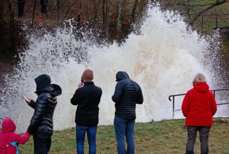 People watch the water release at the Mandelholz dam. Matthias Bein/dpa