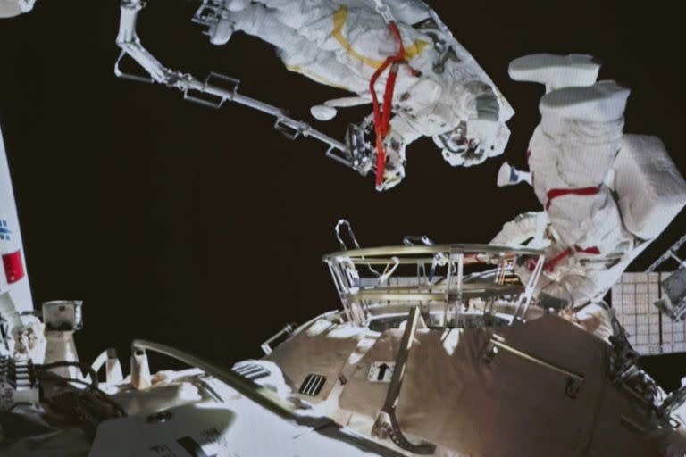 Esta foto tomada de una pantalla muestra a los astronautas chinos Zhai Zhigang y Wang Yaping completando tareas fuera del módulo principal de la estación espacial Tianhe, vistos desde el Centro de Control Aeroespacial de Pekín (Archivo) 