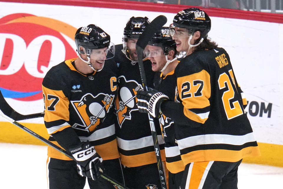 Pittsburgh Penguins' Jake Guentzel, second from right, celebrates with Ryan Graves (27), Bryan Rust (17) and Sidney Crosby (87) after scoring against the Calgary Flames during the third period of an NHL hockey game in Pittsburgh, Saturday, Oct. 14, 2023. (AP Photo/Gene J. Puskar)