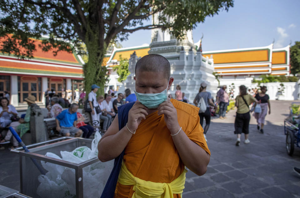 En esta imagen, tomada el 13 de febrero de 2020, un monje budista se ajusta una mascarilla en la cara en el Wat Pho, Bangkok, Tailandia. (AP Foto/Gemunu Amarasinghe)