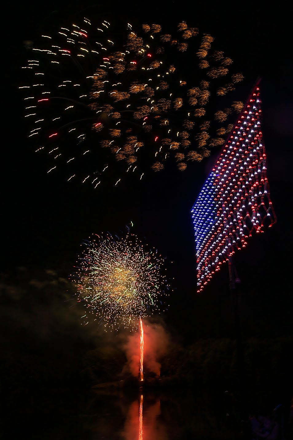 Fireworks explode around an illuminated American Flag during the annual Big Bang Boom 4th of July fireworks show at Lake Storey Park.