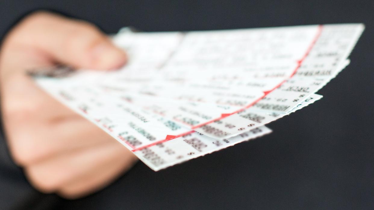 Tickets to a show / event in a hand with a black background.