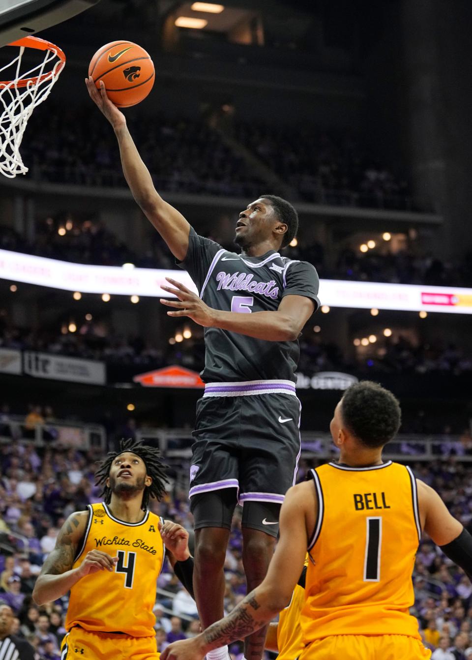 Kansas State guard Cam Carter (5) goes to the basket between Wichita State's Colby Rogers (4) and Xavier Bell (1) for two of his 15 points Thursday night at T-Mobile Center. The Wildcats beat WSU, 69-60.