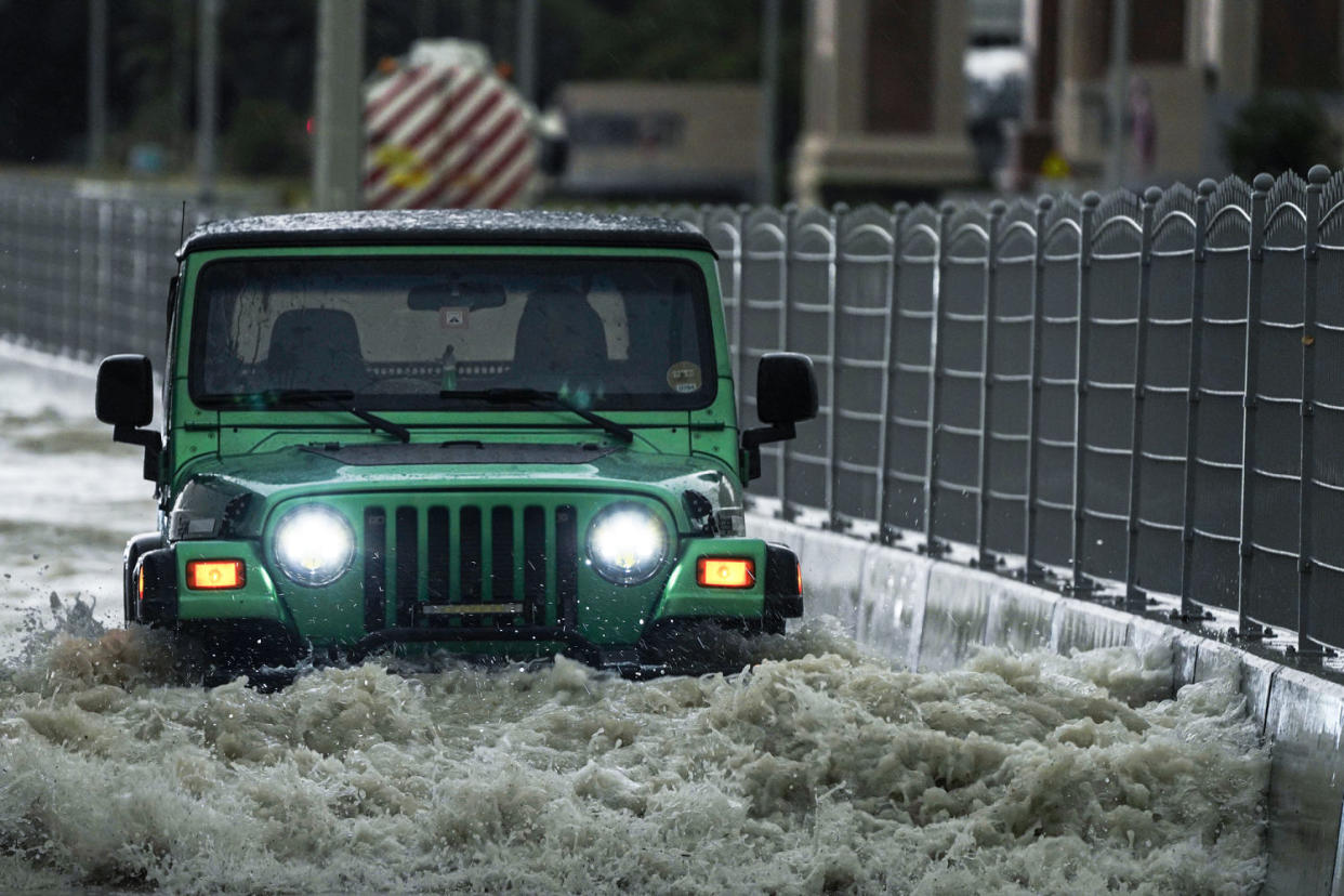 An SUV passes through standing flood water in Dubai (Jon Gambrell / AP)