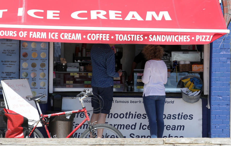 People buy ice creams on Brighton beach, as the UK continues in lockdown to help curb the spread of the coronavirus.