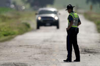 A Missouri state trooper controls traffic, Tuesday, June 28, 2022, on a road leading to the scene of an Amtrak train which derailed after striking a dump truck Monday near Mendon, Mo. (AP Photo/Charlie Riedel)