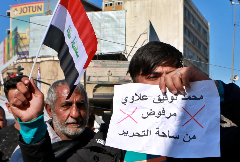 An anti-government protester holds a national flag and a banner with Arabic that reads, "Rejected" during a demonstration against the newly appointed Prime Minister Mohammed Allawi in Tahrir Square, Baghdad, Iraq, Sunday, Feb. 2, 2020. Former communications minister Mohammed Allawi was named prime minister-designate by rival Iraqi factions Saturday after weeks of political deadlock. (AP Photo/Khalid Mohammed)