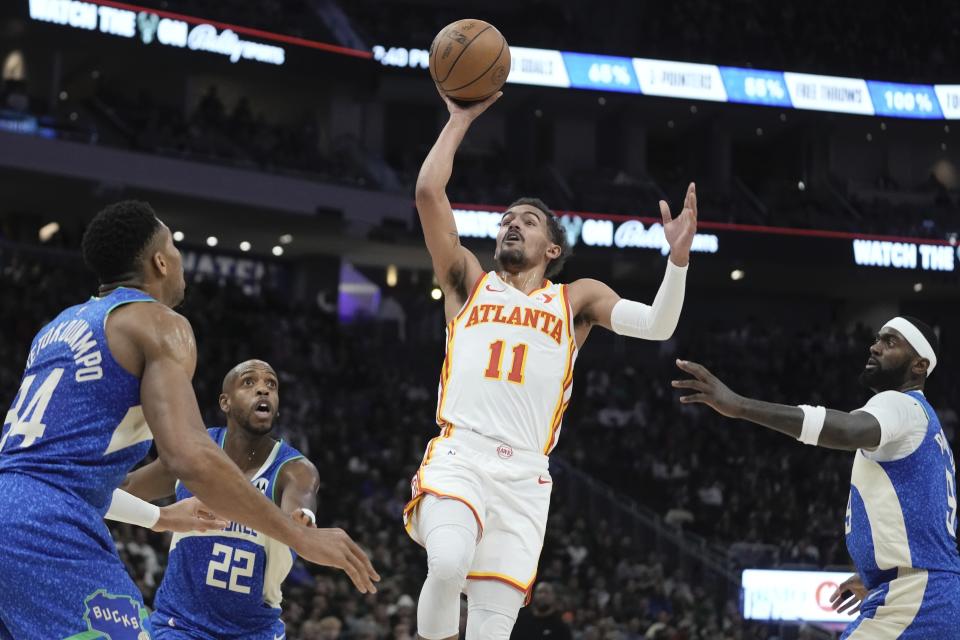 Atlanta Hawks' Trae Young shoots between Milwaukee Bucks' Giannis Antetokounmpo, Khris Middleton and Bobby Portis during the first half of an NBA basketball game Saturday, Dec. 2, 2023, in Milwaukee. (AP Photo/Morry Gash)