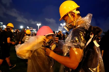 A young protestor helps his girlfriend to put on her gear as they take part in a rally outside the government headquarters in Hong Kong