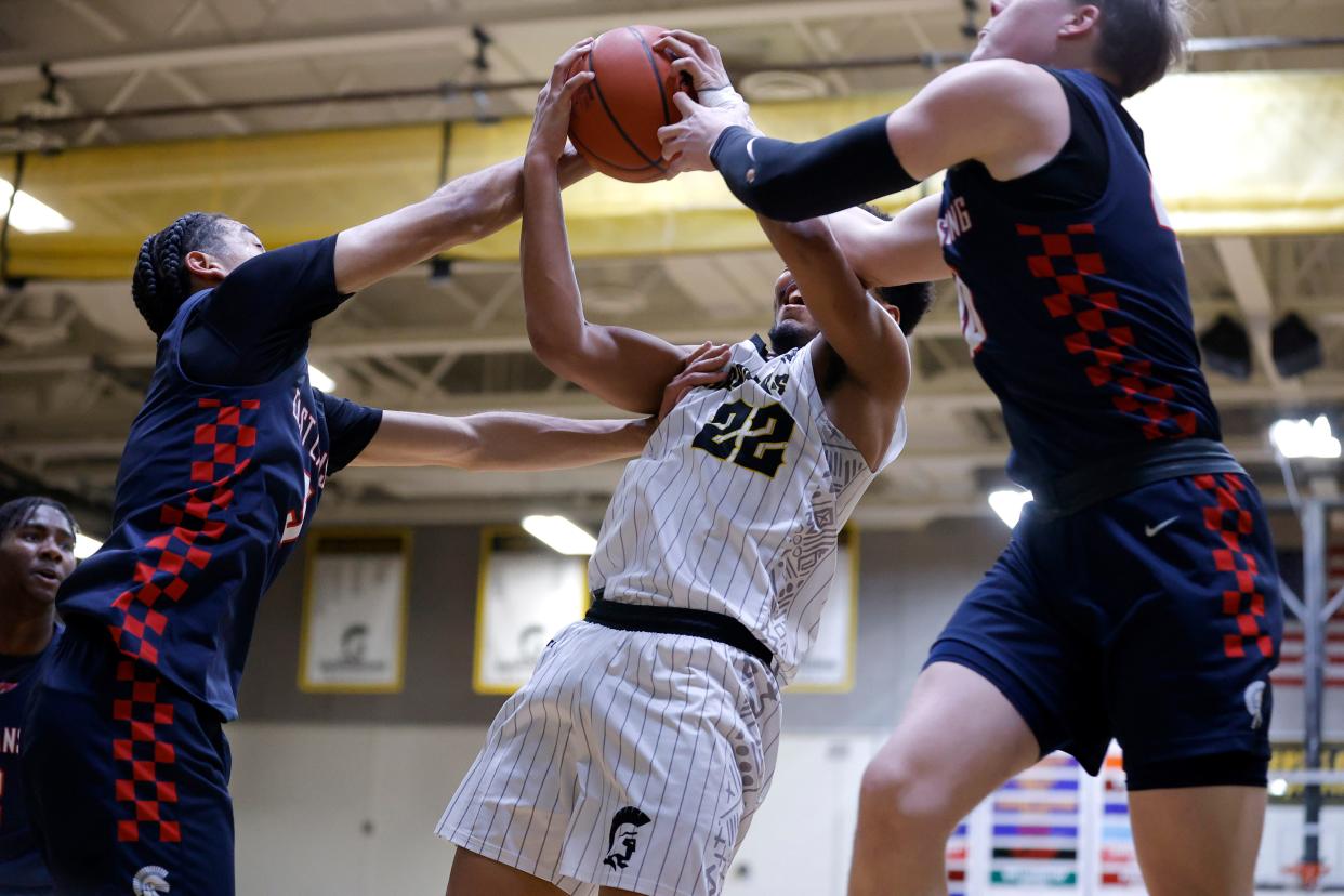 Waverly's Derek Thomas II, center, and East Lansing's Cam Hutson, left, and Charlie Baker fight for a rebound, Friday, Feb. 9, 2024, at Waverly High School.