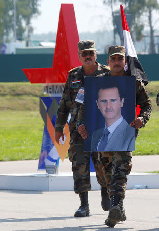 FILE PHOTO: Syrian soldiers carry a portrait of the President Bashar al-Assad during the opening ceremony of the International Army Games 2018, in Alabino, outside Moscow, Russia, July 28, 2018. REUTERS/Sergei Karpukhin/File Photo