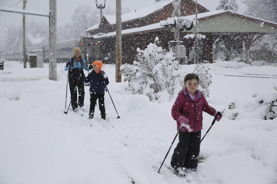 Beth Reilly, background, cross country skies with her two children, Noah, 7, in the middle, and Annelies, 5, during a snowstorm in Waterbury, Vt., on Tuesday, March 14, 2023. They were taking advantage of a snow day caused by the winter storm that was dropping heavy, wet snow across the Northeast. The storm at caused a plane to slide off the runway and led to hundreds of school closings, canceled flights and thousands of power outages in parts of the Northeast on Tuesday. (AP Photo/Wilson Ring)