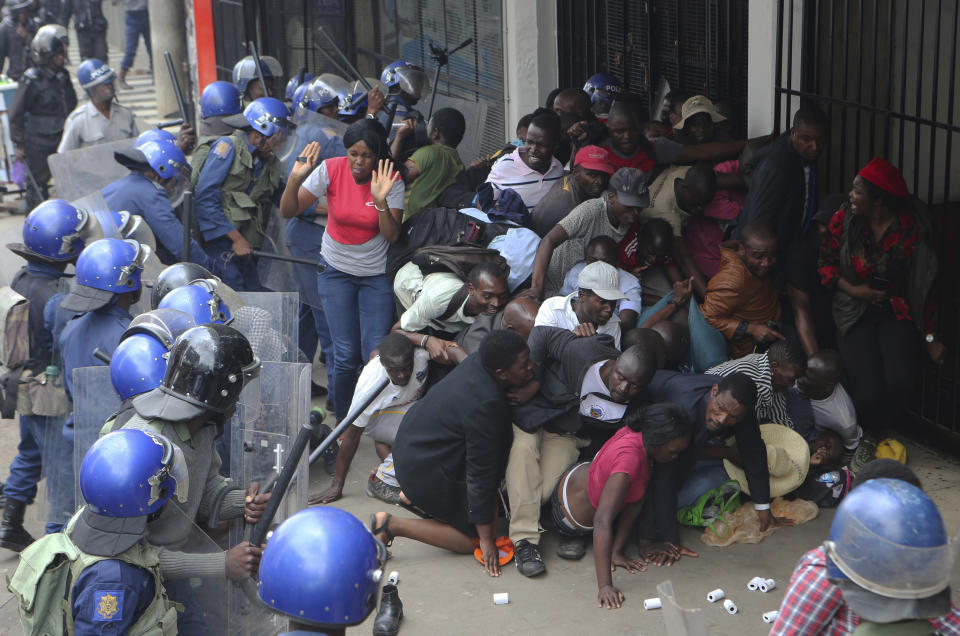 Police surround opposition party supporters who had gathered to hear a speech by the country's top opposition leader in Harare, Wednesday, Nov. 20, 2019. Zimbabwean police with riot gear fired tear gas and struck people who had gathered at the opposition party headquarters to hear a speech by the main opposition leader Nelson Chamisa who still disputes his narrow loss to Zimbabwean President Emmerson Mnangagwa. (AP Photo/Tsvangirayi Mukwazhi)