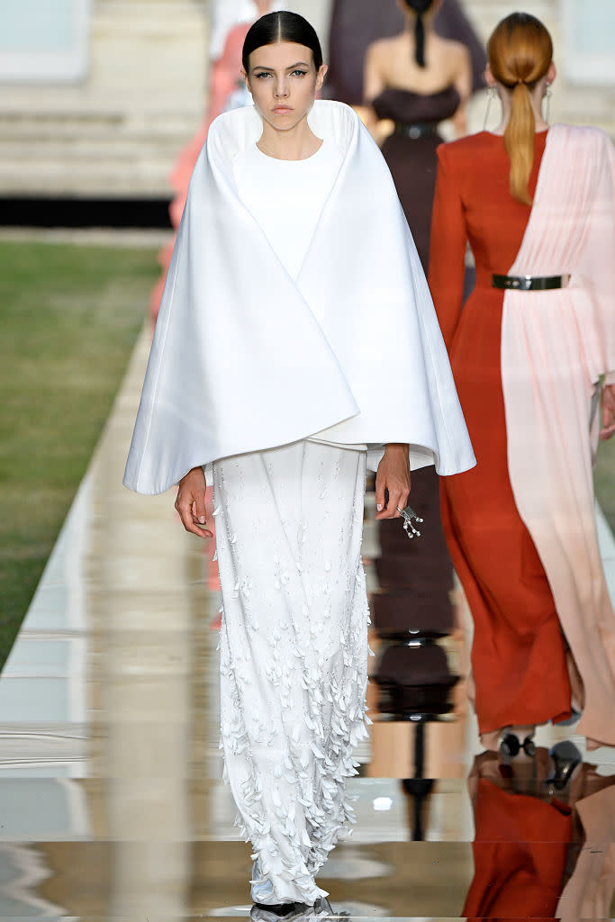 <p>Model wears a simple white cape over a white gown from the Givenchy fall 2018 couture collection. (Photo: Getty Images) </p>