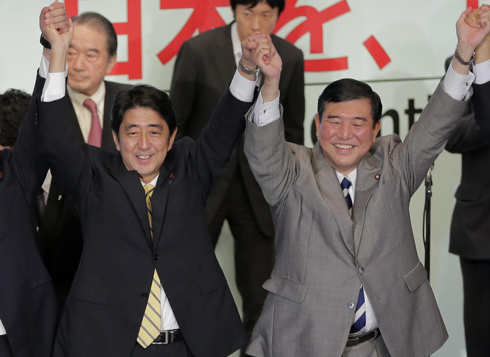 Former Japanese Prime Minister Shinzo Abe, left, joins hands with a contender Shigeru Ishiba after winning the party leadership election of Japan's Liberal Democratic Party in Tokyo Wednesday, Sept. 26, 2012. Abe, known as a hawk and nationalist, defeated ex-defense chief Ishiba in a run-off election Wednesday by a vote of 108-89 to become president of the main opposition Liberal Democratic Party. (AP Photo/Itsuo Inouye)