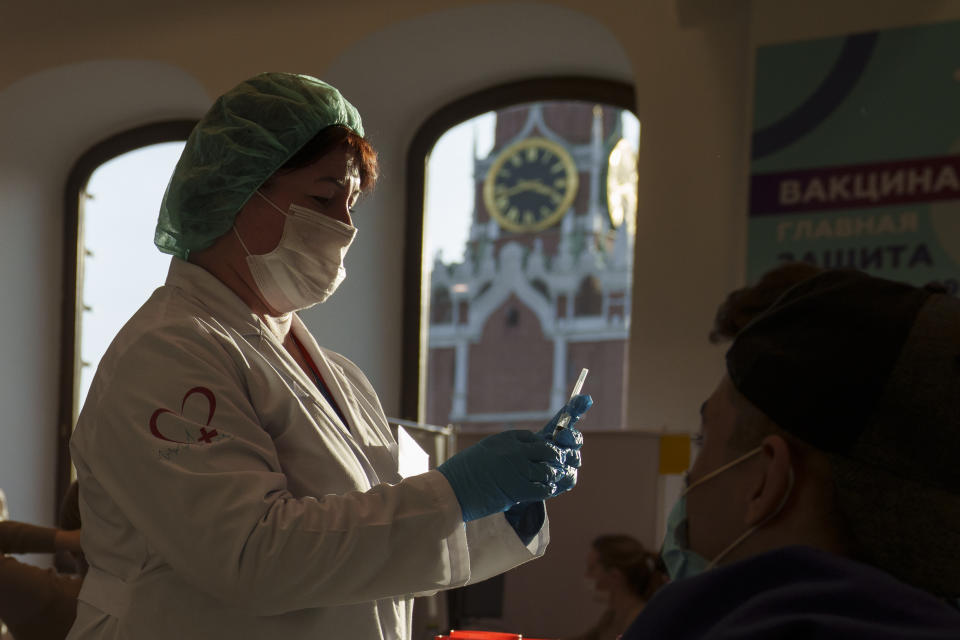 A medical worker prepares a shot of Russia's Sputnik Lite coronavirus vaccine at a vaccination center in the GUM, State Department store, in Red Square with the Spasskaya Tower in the background, in Moscow, Russia, Tuesday, Oct. 26, 2021. The daily number of COVID-19 deaths in Russia hit another high Tuesday amid a surge in infections that forced the Kremlin to order most Russians to stay off work starting this week. (AP Photo/Pavel Golovkin)