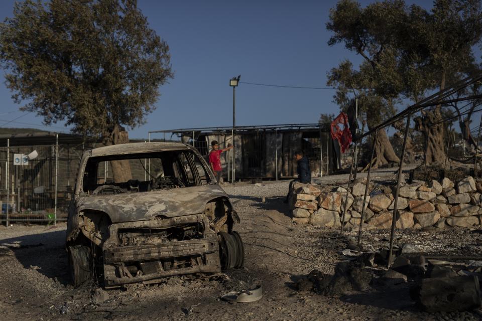 Migrant boys stand in the burned Moria refugee camp on the northeastern island of Lesbos, Greece, Thursday, Sept. 10, 2020. A second fire in Greece's notoriously overcrowded Moria refugee camp destroyed nearly everything that had been spared in the original blaze, Greece's migration ministry said Thursday, leaving thousands more people in need of emergency housing. (AP Photo/Petros Giannakouris)