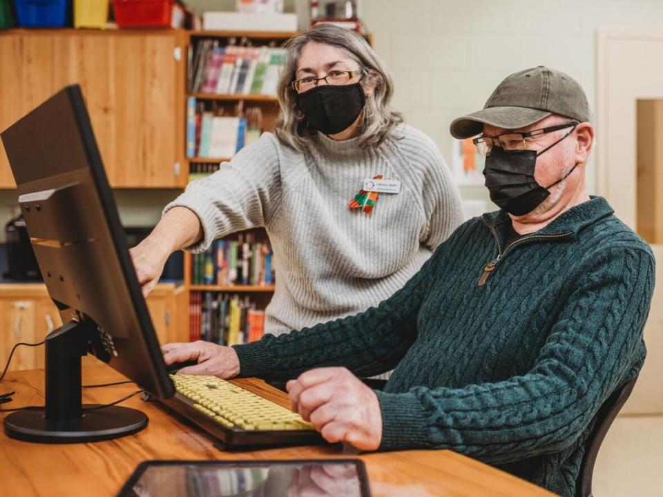 Sheila Newell-Fagan, branch assistant at the Westville Library, helps library patron Albert MacDonald access virtual health care. (Submitted by Pictou-Antigonish Reginal Library - image credit)